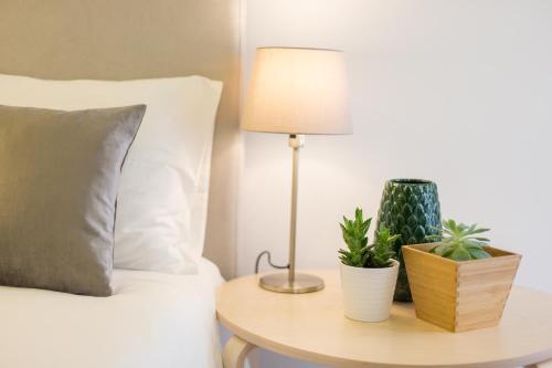 a bed with a lamp and two plants on a table at Amalia Studios in Lisbon