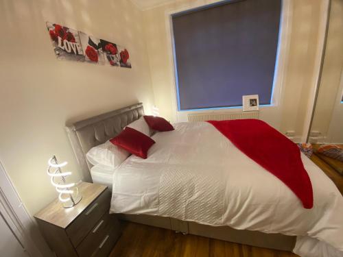a bedroom with a bed with red pillows and a window at irhaa in Mossend