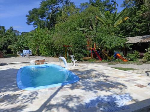 uma pequena piscina num quintal com parque infantil em Suites Brejauva em Ubatuba