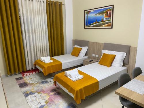 ein Hotelzimmer mit 2 Betten und einem Tisch in der Unterkunft Kevin’s Lungomare Apartment in Vlorë