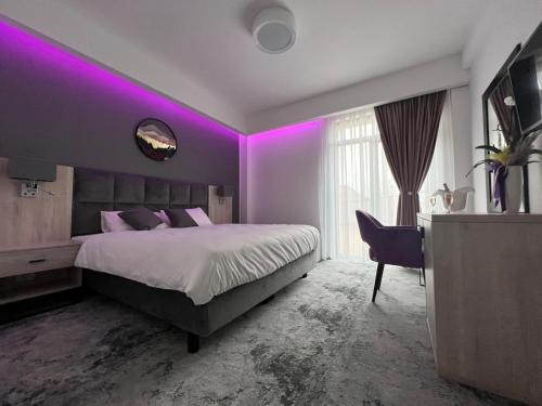 a purple room with a bed and a desk at Majestic Boutique Hotel in Baile Felix