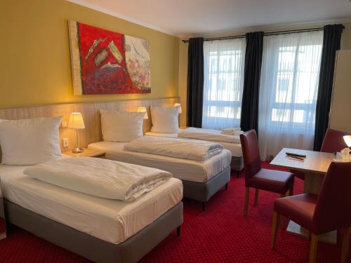 a hotel room with three beds and a table and chairs at Palm Premium Hotel & Apartments in Düsseldorf