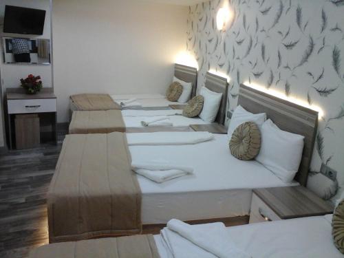 three beds in a room with a wall with birds on it at Olimpiyat Hotel Izmir in Izmir