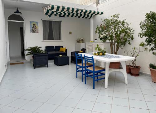 ein Wohnzimmer mit einem weißen Tisch und blauen Stühlen in der Unterkunft Casa Fiorella - Casa indipendente centro Anacapri in Anacapri