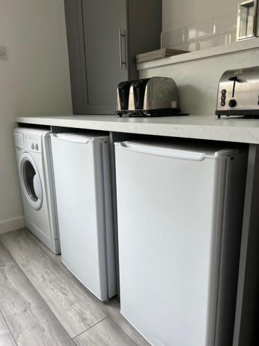 a kitchen with a washer and dryer under a counter at Five Bedroom Five Bathroom House - Dalkeith in Dalkeith