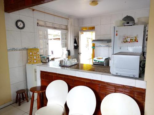 - une cuisine avec des chaises blanches et un réfrigérateur blanc dans l'établissement Casa na Ilha da Crôa/Barra de Santo Antônio, à Barra de Santo Antônio