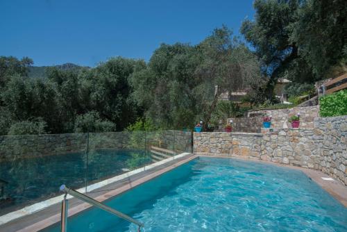 a large swimming pool with a stone retaining wall and a stone wall at Villa Douros in Parga