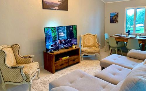 a living room with a flat screen tv and a table at Casa Mar Quente in Ribeira Quente