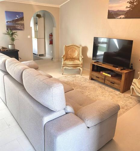 a living room with a couch and a flat screen tv at Casa Mar Quente in Ribeira Quente
