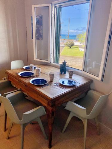 a wooden table with chairs and a table with plates on it at Casa Mar Quente in Ribeira Quente