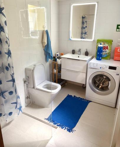 a bathroom with a toilet and a sink and a washing machine at Casa Mar Quente in Ribeira Quente