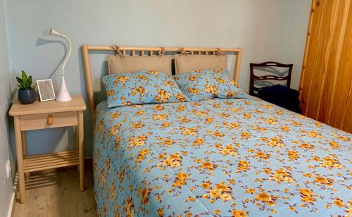 a bed with a blue comforter with flowers on it at Casa Mar Quente in Ribeira Quente