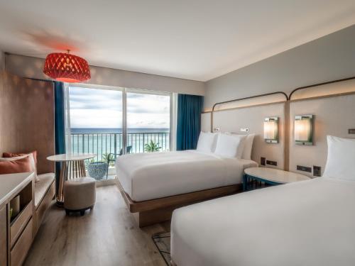 a hotel room with two beds and a balcony at Crowne Plaza Resort Guam in Tumon