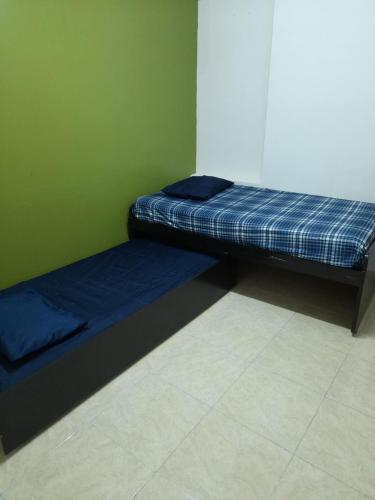 two beds in a room with a green wall at Special HOEStel in Monterrey! in Monterrey