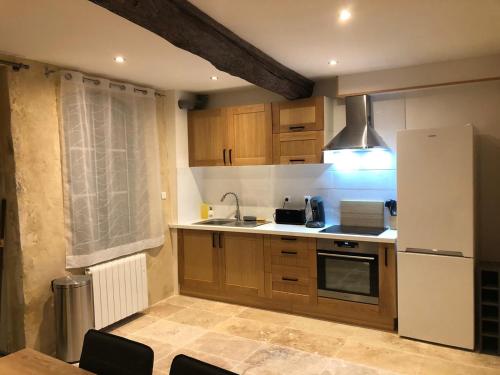 une cuisine avec des armoires en bois et un réfrigérateur blanc dans l'établissement Superbe Appart Rustique, à Arles