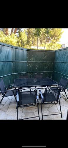une table et des chaises assises devant une clôture dans l'établissement Residence Eden park, à Cannes