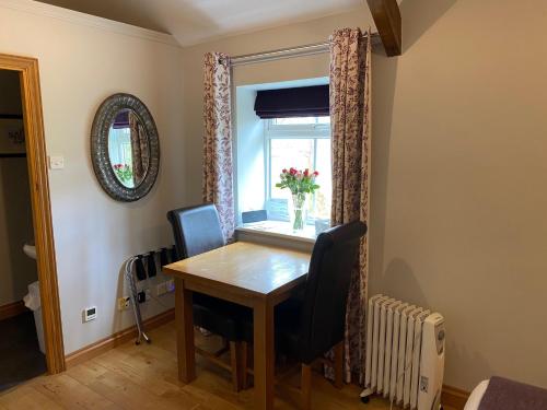 a dining room table with a vase of flowers on a window at The Bothy at Ivy Cottage in Haltwhistle