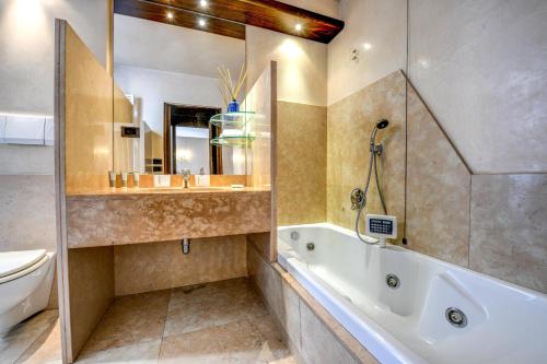 a bathroom with a tub and a sink and a toilet at Prestige Suite Sirmione in Sirmione