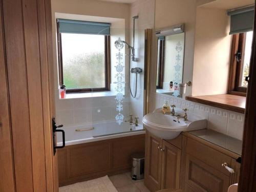 ein Bad mit einem Waschbecken, einer Badewanne und einem Fenster in der Unterkunft Sycamore Cottage in Appleby