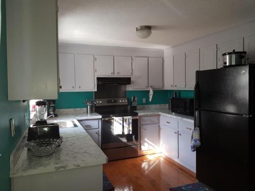 a kitchen with white cabinets and a black refrigerator at Thompson House Cape Cod in South Yarmouth