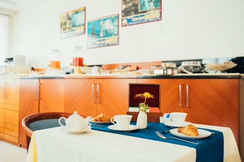 a table with croissants and cups and saucers on it at Arcangelo Roof Hotel in Rimini