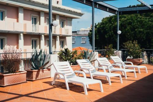 a row of white chairs sitting on a patio at Arcangelo Roof Hotel in Rimini