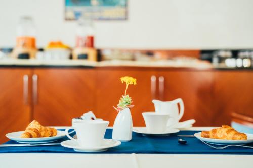 a table with plates and cups and croissants at Arcangelo Roof Hotel in Rimini