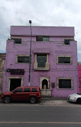 un edificio púrpura con un todoterreno rojo estacionado frente a él en Hotel México en Morelia