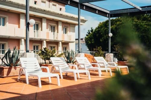 a row of white chairs sitting on a patio at Arcangelo Roof Hotel in Rimini