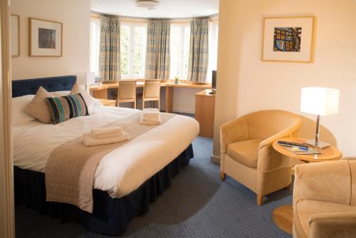 a hotel room with a bed and a chair at Madingley Hall in Cambridge