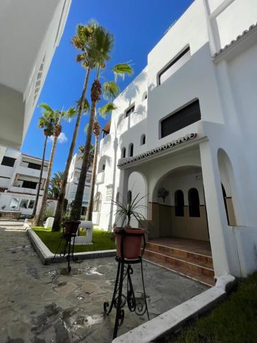 a building with palm trees in front of it at Complexe Al AMINE plage -rifiyine in Dar Merah Deriba