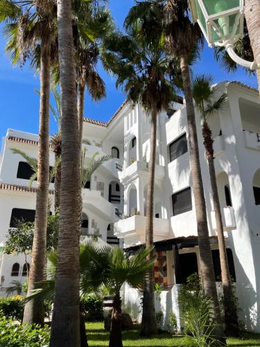 a building with palm trees in front of it at Complexe Al AMINE plage -rifiyine in Dar Merah Deriba