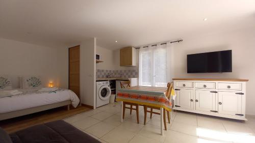 a bedroom with a bed and a kitchen with a table at Gite La clef du Sud in Salernes