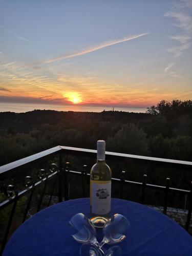 a bottle of wine sitting on a table with the sunset at Santa Maria Rooms in Agios Nikitas