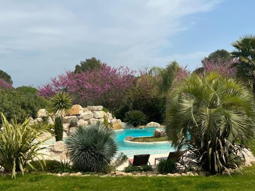 een zwembad in een tuin met 2 stoelen en palmbomen bij Villa des Cabres in Lunel