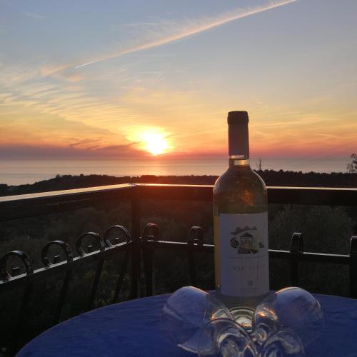 a bottle of wine sitting on a table with the sunset at Santa Maria Rooms in Agios Nikitas