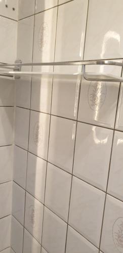 a white tiled bathroom with a glass shower stall at Maison entre relooking et modernité dans un cadre verdoyant pour amoureux de grands espaces in Nogent-sur-Vernisson
