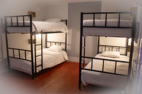 a room with two bunk beds with white sheets at Casa Kutimuy in Ayacucho