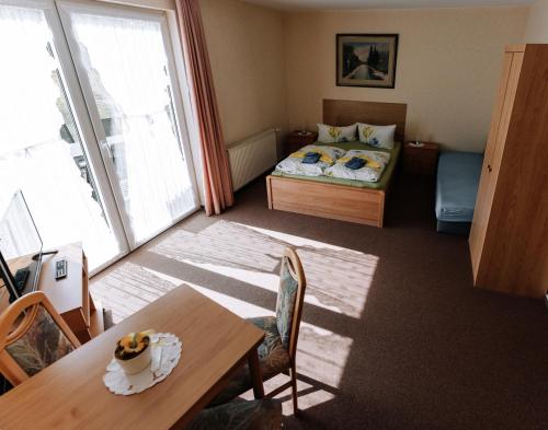 a small room with a bed and a table and a dining room at Pension Kristall in Elbingerode