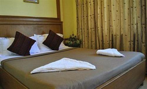a bed with two white towels on top of it at Hotel Roopa in Mysore
