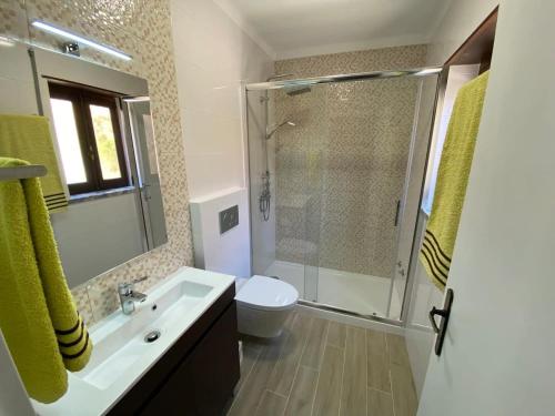 uma casa de banho com um chuveiro, um lavatório e um WC. em O Cantinho do Sol (Estúdio Chocolate) na Lourinhã