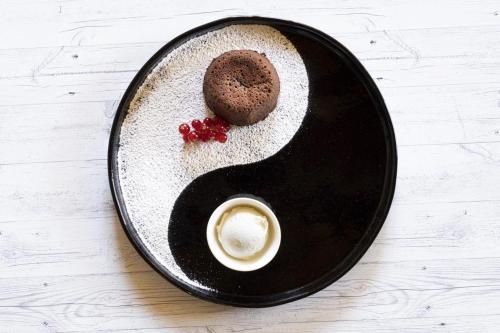 a black plate with a chocolate cookie and a cup of coffee at Agriturismo Ortesida in Morbegno