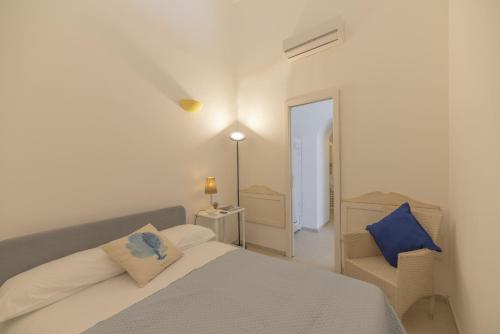 a white bedroom with a bed and a chair at Capri center holidays in Capri