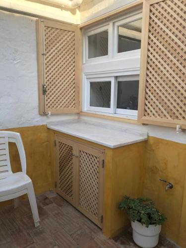 タヴィラにあるCasa rústica com jardim privadoの窓と白い椅子付きのキッチン