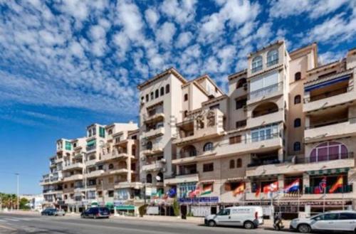 a large apartment building with cars parked in front of it at Beautiful apartment near LaMata Beach with PANORAMA SEA view!!! in Torrevieja
