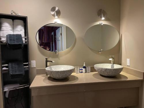 two sinks in a bathroom with two mirrors at Globetrotters B&B in Niagara-on-the-Lake