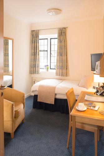 a hotel room with a bed and a desk at Madingley Hall in Cambridge