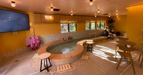 a hot tub in a room with a tv and a table at Kowakuen Haruka in Matsuyama