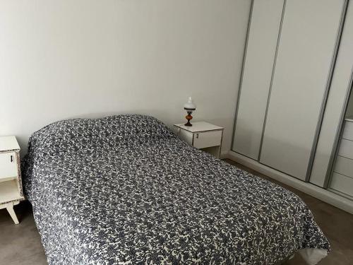 1 dormitorio con 1 cama con edredón blanco y negro en Village en Tandil