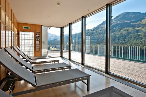 a gym with large windows and a balcony with mountains at Hotel Schweizerhof St. Moritz in St. Moritz